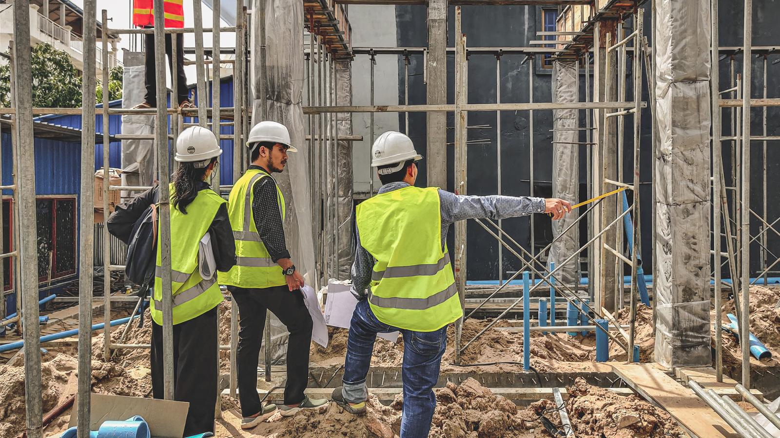 Engineering team inspects pipe work at construction site. 