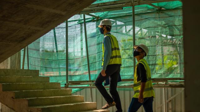 EMI Staff walking up a concrete stair on a site under construction.