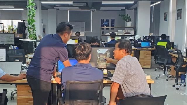 Senior engineer mentors two young Khmer engineers.